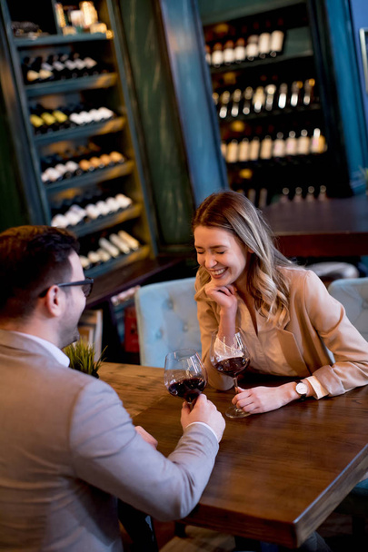 赤ワインのグラスを片手にレストランでランチを楽しむ若いカップル - 写真・画像