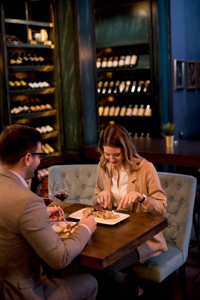 Прекрасна молода пара вечеряє в ресторані і п'є червоне вино
 - Фото, зображення