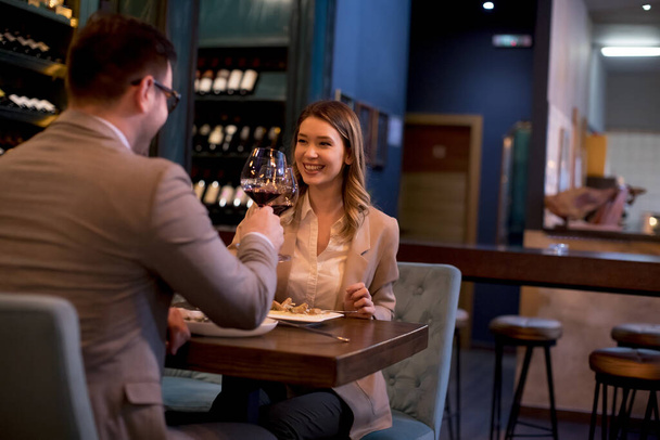 Прекрасная молодая пара ужинает в ресторане и пьет красное вино
 - Фото, изображение