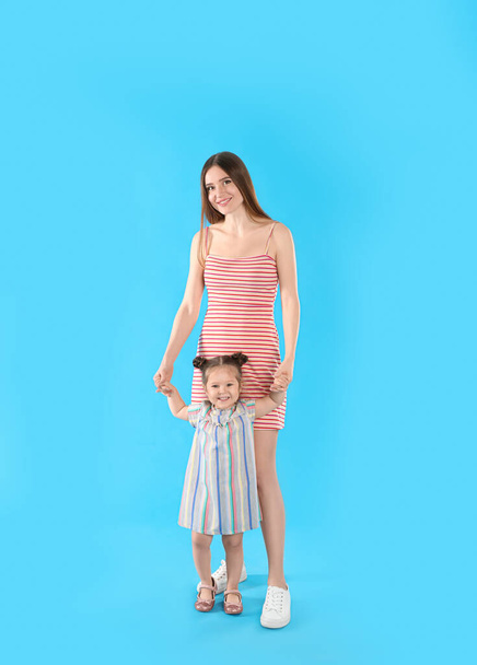 Young mother and little daughter on blue background - Foto, Imagem