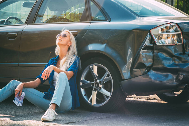 La chica se sienta en el coche roto con billetes de dinero para la reparación
. - Foto, Imagen