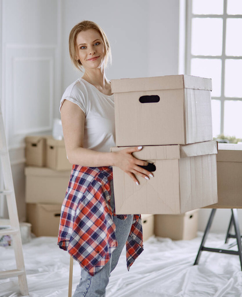 Une belle jeune femme célibataire déballer des boîtes et emménager dans une nouvelle maison - Photo, image