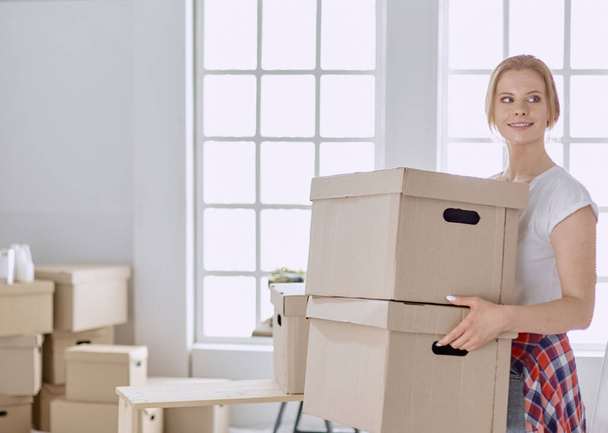 Güzel bekar bir kadın kutuları açıyor ve yeni bir eve taşınıyor. - Fotoğraf, Görsel