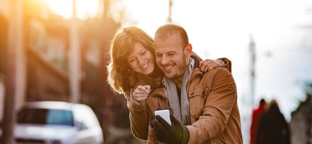 Modernes urbanes Paar posiert auf der Straße und nutzt Smartphone. - Foto, Bild