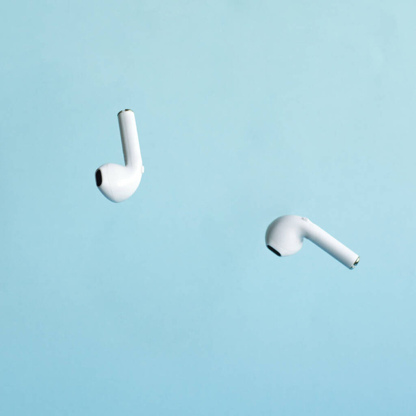 Levitating wireless headphones on a cyanite background. Selective focus. Gadgets. New technologies. - Photo, Image