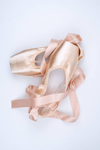 Τα ροζ σατέν παπούτσια μπαλέτου σε λευκό φόντο, δείχνουν λεπτομέρεια, για εξάσκηση - Φωτογραφία, εικόνα