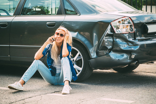 girl sits on the road, near the broken car and calls on the phone, calling for help. - Foto, Imagen