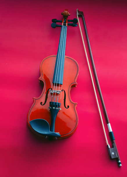 Деревянная скрипка и лук на красном фоне, показать детали строчки insgrument, художественный стиль
 - Фото, изображение