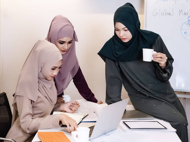 Мусульманская деловая женщина, занимающаяся бумажной работой вместе, в конференц-зале, в офисе. - Фото, изображение
