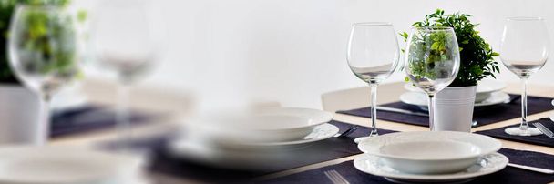 Close up view table setting served for dinner on violet place mats empty wine glasses plates flatware, no people. Horizontal image copy space for advertisement text, domestic life dining room concept - Photo, image