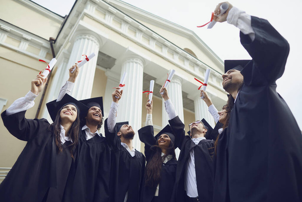 Scrolls diplomas in the hands of graduates. - Фото, изображение
