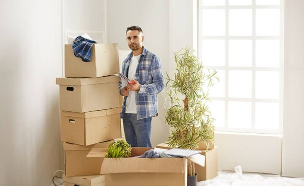 Jóképű férfi dobozokkal az új lakásban, miután elköltözött. - Fotó, kép