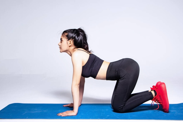The beautiful wearing exercise suit,put hand and knees on mat raise face up and breath,The Cat-Cow pose in yoga,posing basic pattern,at studio - Photo, image