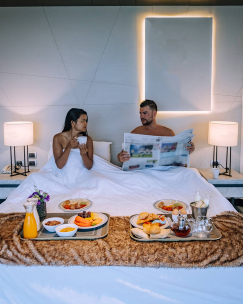 couple having breakfast in bed, men and woman in luxury room and white bed having breakfast in bed - Foto, Bild