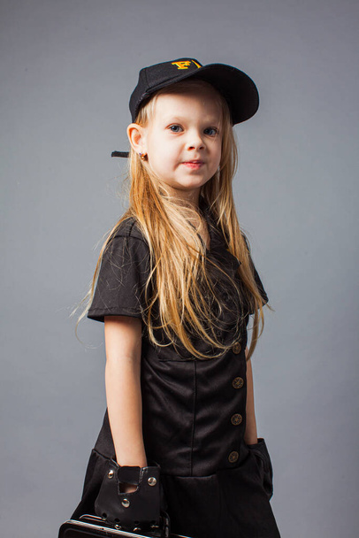 School girl wears black costume and cap, and plays in criminal agent. Child choose to be Fbi agent. - Foto, Bild