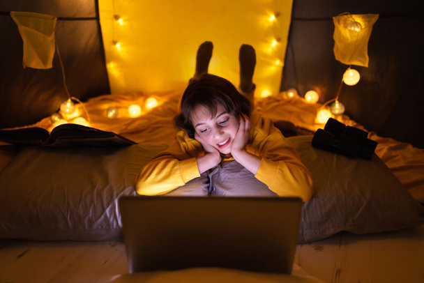 Piccola ragazza di 11 anni utilizzando il computer portatile sotto la sua tenda fatta in casa all'interno del soggiorno
. - Foto, immagini
