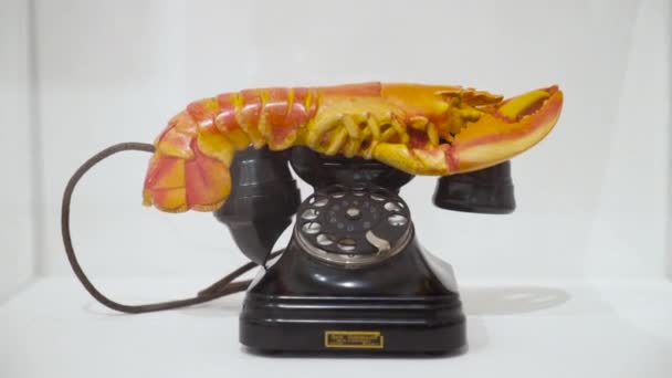 Retro-Telefon mit ungewöhnlichem Hörer. Handeln. Schwarzes Retro-Telefon mit krabbenförmigem Hörer steht auf weißem Museumsfenster. Ungewöhnliches Retro-Handy mit Spielzeugkrabbe statt Schlauch - Filmmaterial, Video