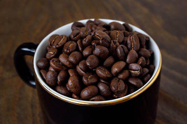 黒いカップと周りのコーヒー豆.トップビュー、木製の背景。コーヒーと磁器. - 写真・画像