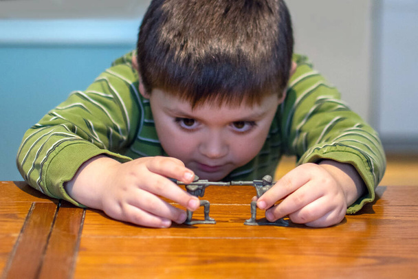 nuori poika leikkii kahdella lelusotilaalla muoviaseilla
 - Valokuva, kuva