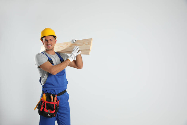 Handsome carpenter with wooden planks on light background. Space for text - Foto, afbeelding