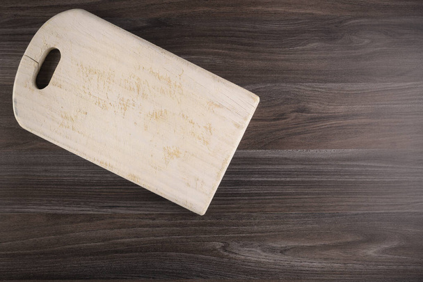 Top view of wooden cutting board on old dark wood countertop. - 写真・画像