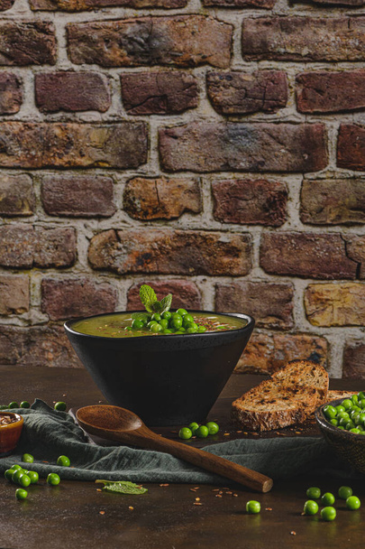Green pea soup with linseed and pumpkin and sunflower seeds on a rustic kitchen countertop. - Φωτογραφία, εικόνα
