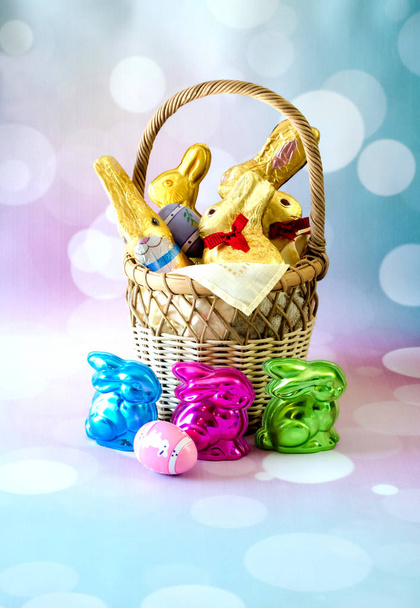 Un cesto decorativo è pieno di coniglietti di Pasqua al cioccolato e uova colorate
 - Foto, immagini