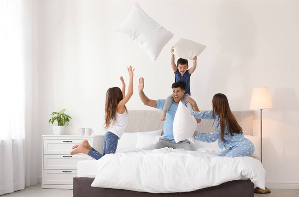Happy family having pillow fight in bedroom - 写真・画像
