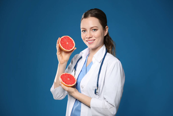 Nutritionist with ripe grapefruit on blue background - Foto, afbeelding