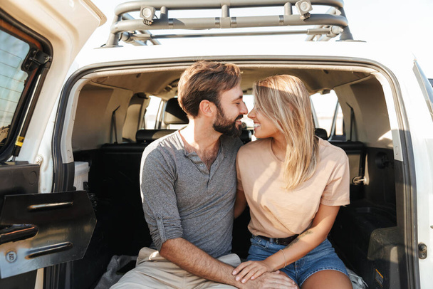 Image of a positive pleased happy young amazing loving couple outdoors hugging in car at the beach. - Photo, Image