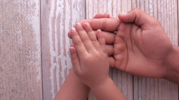 top view of child hand on father hand on table  - Footage, Video