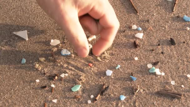 Person reaches down and picks up plastic pollution washed up from the Pacific Ocean at the Oregon Coast. - Footage, Video