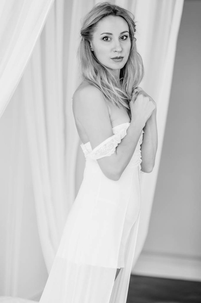 a blonde girl in a white dress on a white fabric  - Zdjęcie, obraz