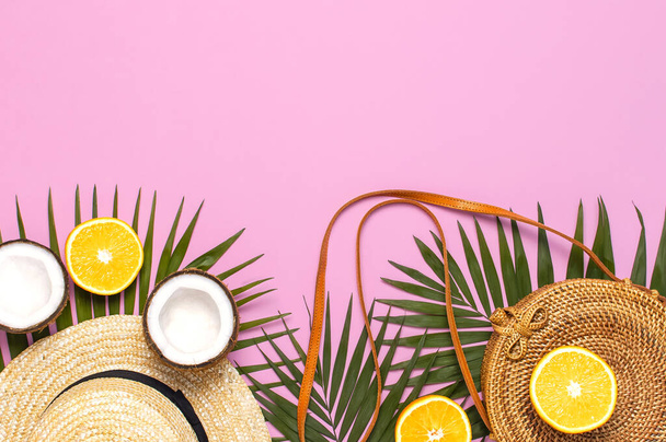 Summer fashion flat lay. Round trendy rattan bag, tropical palm leaves, straw hat, coconut, orange on pink background. Top view, copy space. Trendy bamboo bag. Creative background, vacation concept. - Foto, Imagen
