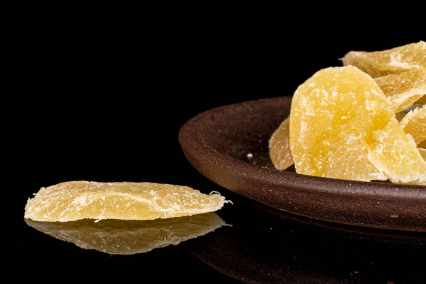 Lot of slices of dried yellow pineapple with brown ceramic coaster isolated on black glass - Fotografie, Obrázek