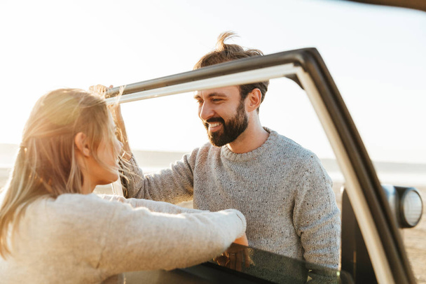 Foto di giovane felice allegra coppia amante ottimista all'aperto in spiaggia vicino alla macchina
. - Foto, immagini