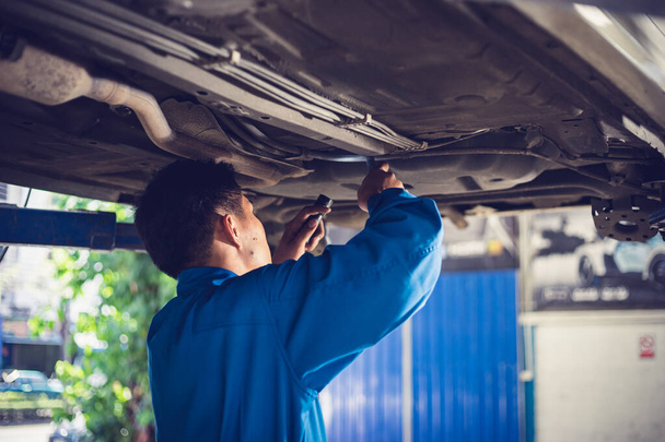 Tamirci tamirhanedeki arabayı tamir ediyor. Otomobil servisi kavramları - Fotoğraf, Görsel