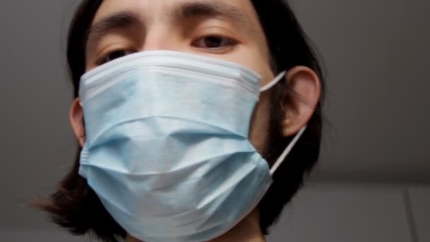 Man wearing a surgical face mask covering the lower half of his face.medical and healthcare concept. He talks looking direct at the camera with a serious expression. Guy shake his head saying no - Metraje, vídeo
