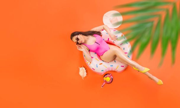 Pretty girl relaxes on the donut inflatable circle under the palm tree. Summer travel concept. - Foto, Imagem
