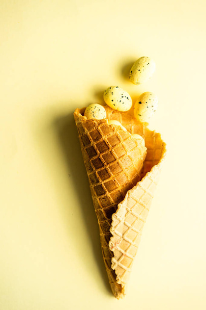 Concepto de tarjeta de Pascua con cono de gofre lleno de huevos de Pascua fondo de color pastel con espacio de copia
 - Foto, imagen