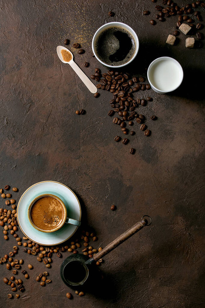 Variety of paper cups of americano coffee and milk versus turkish coffee in ceramic cup and cezve, recycled wooden spoon of cane sugar, coffee beans over dark texture background. Flat lay, space - Fotoğraf, Görsel