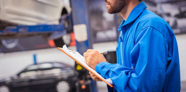 Mechanic checking car and write down in the paper on clipboard. Auto car service concepts - 写真・画像