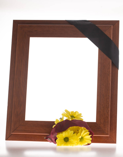 Cornice marrone con nastro di lutto e fiori gialli
 - Foto, immagini