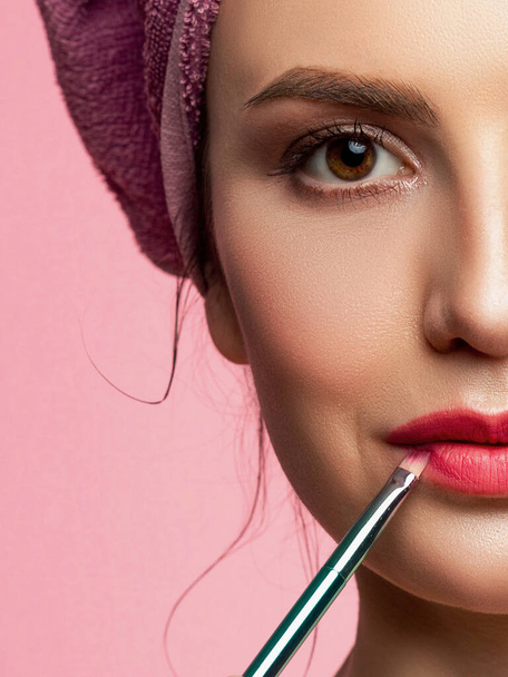 Makeup artist applies red lipstick. Beautiful female face. Hand of a make-up master painting lips of a young girl beauty model. Makeup in progress - Fotoğraf, Görsel