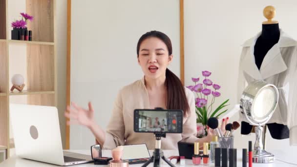 4k videó Híres bloggerről. Vidám női vlogger mutatja kozmetikai termékek, miközben rögzíti a videót a mindennapi smink tutorial. a munkahelyen. - Felvétel, videó
