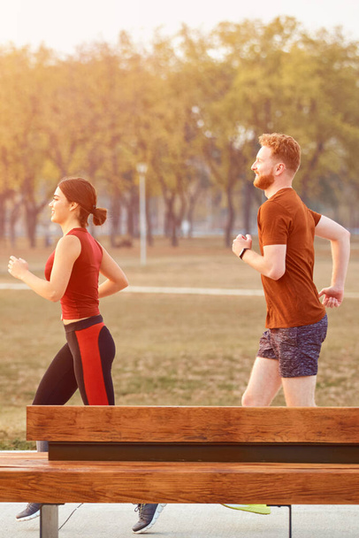 Modern woman and man jogging / exercising in urban park. - Фото, изображение