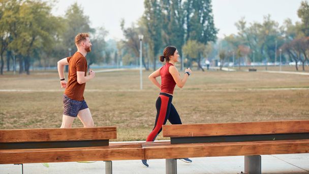 Сучасна жінка і чоловік біжить / займається спортом в міському парку
. - Фото, зображення