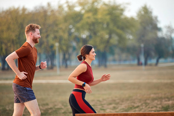 Современная женщина и мужчина бег трусцой / упражнения в городском парке. - Фото, изображение