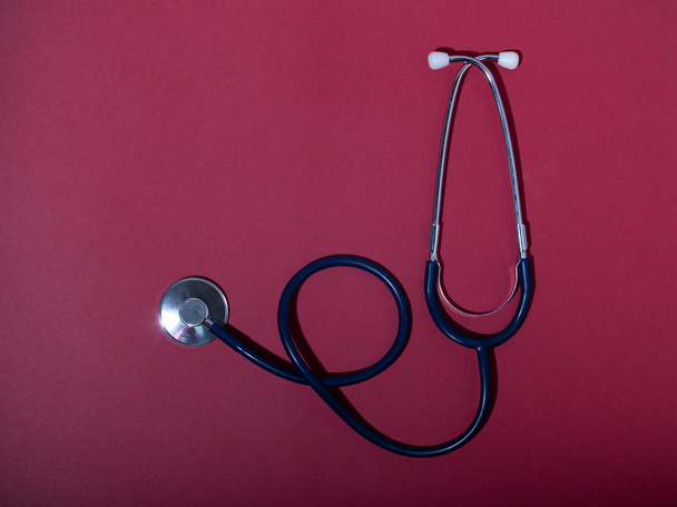 Medical stethoscope or phonendoscope  isolated on red background. Close-up of a stethoscope. flat lay. your text here - 写真・画像
