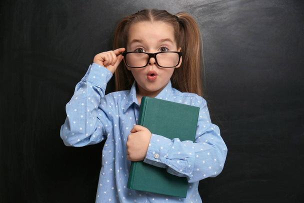Cute little child wearing glasses near chalkboard. First time at school - Foto, Imagen